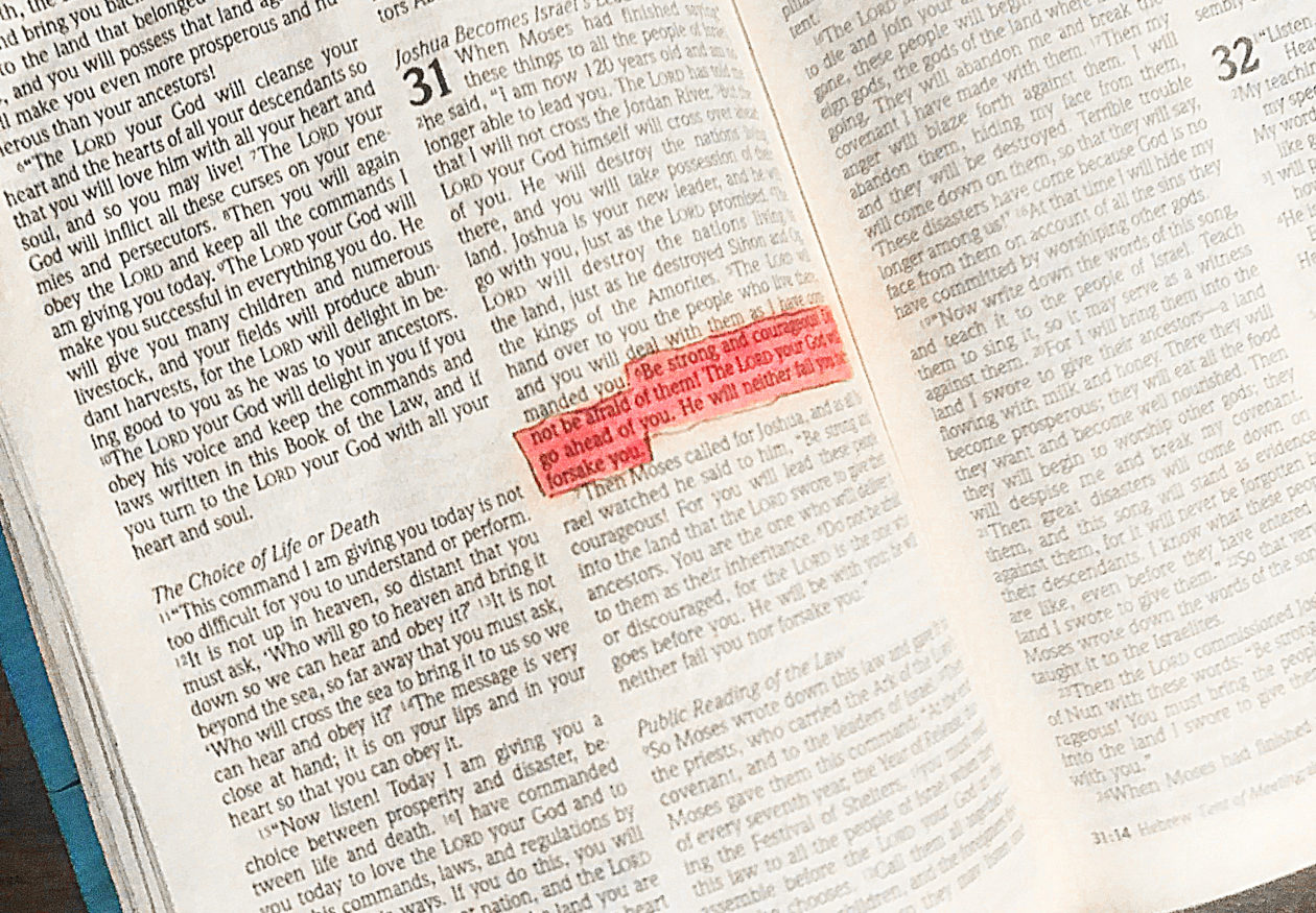 A well used Bible with Deuteronomy 31:6 highlighted in pink.